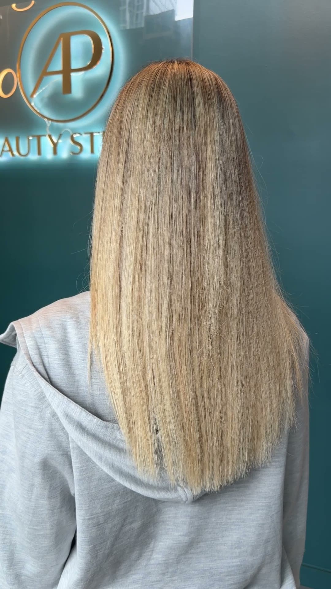 Long, straight highlighted hair in front of the AP Beauty Studio sign