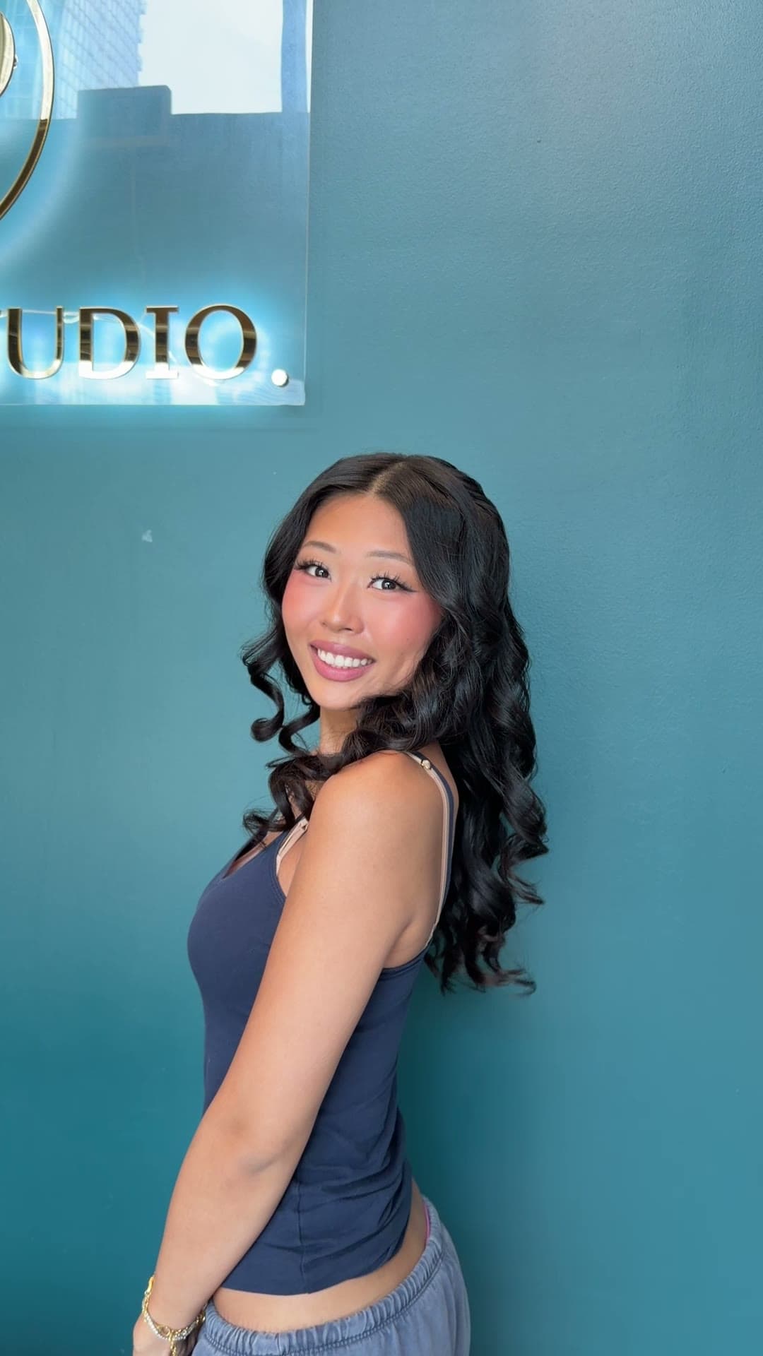 A client smiling after her colour, with glossy dark curls
