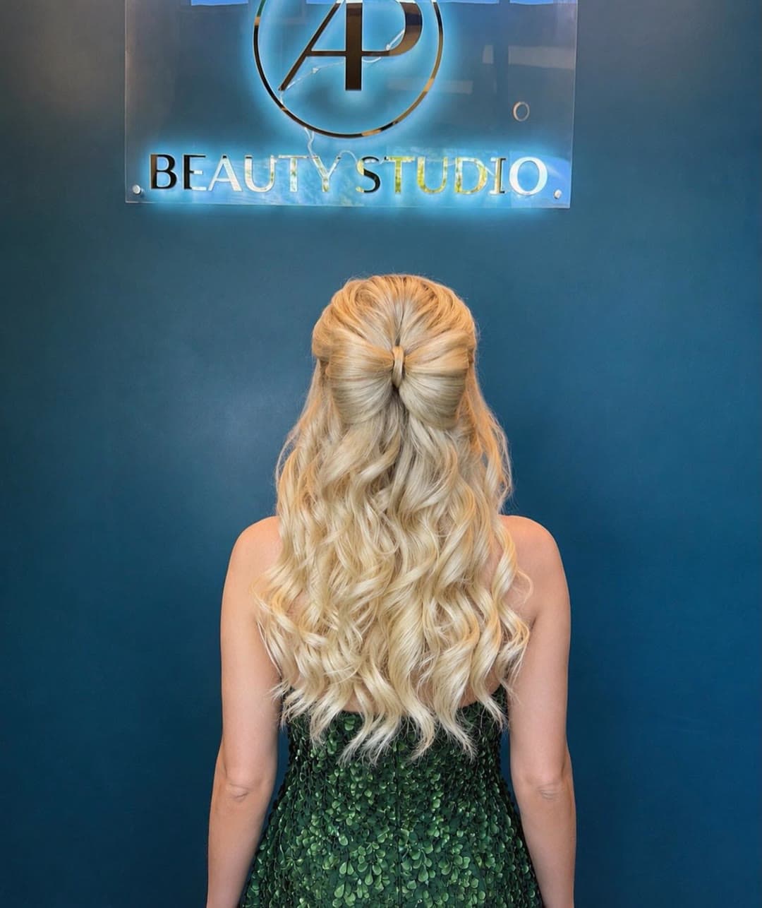 Blonde curls styled half up, in front of the AP Beauty Studio sign in Vaughan