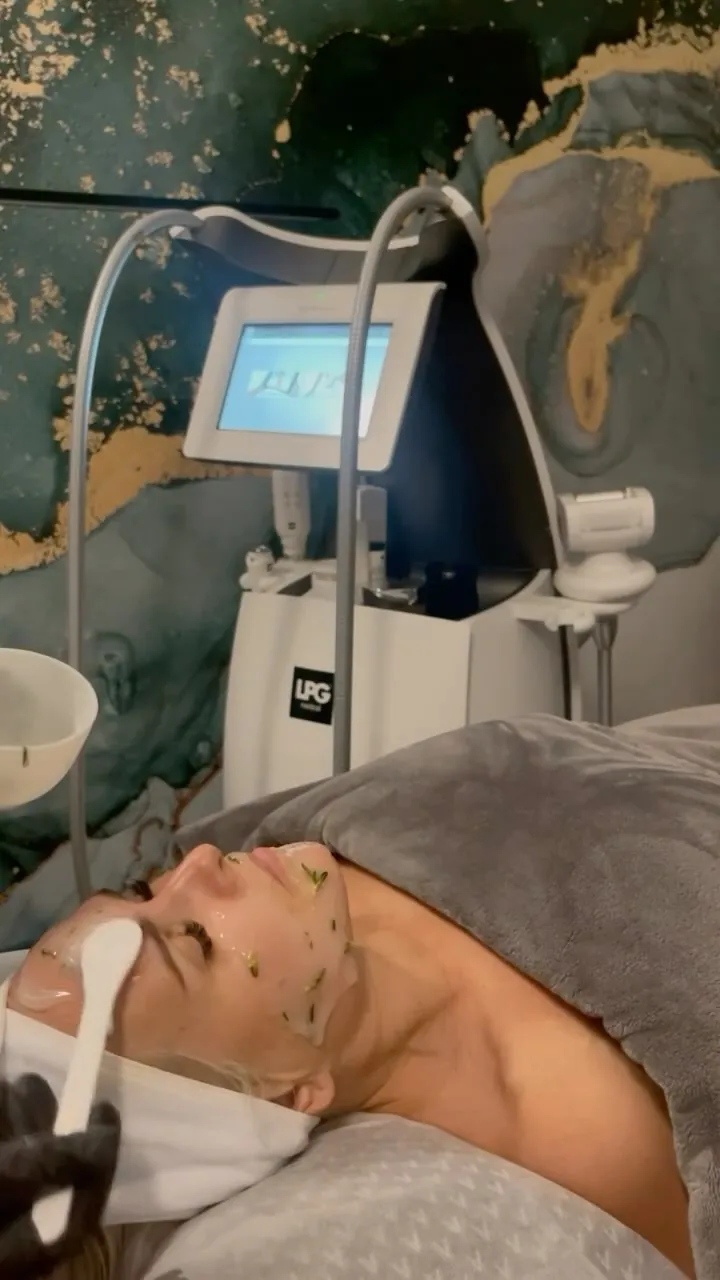 Client relaxing during an LPG face session, with the LPG device beside her